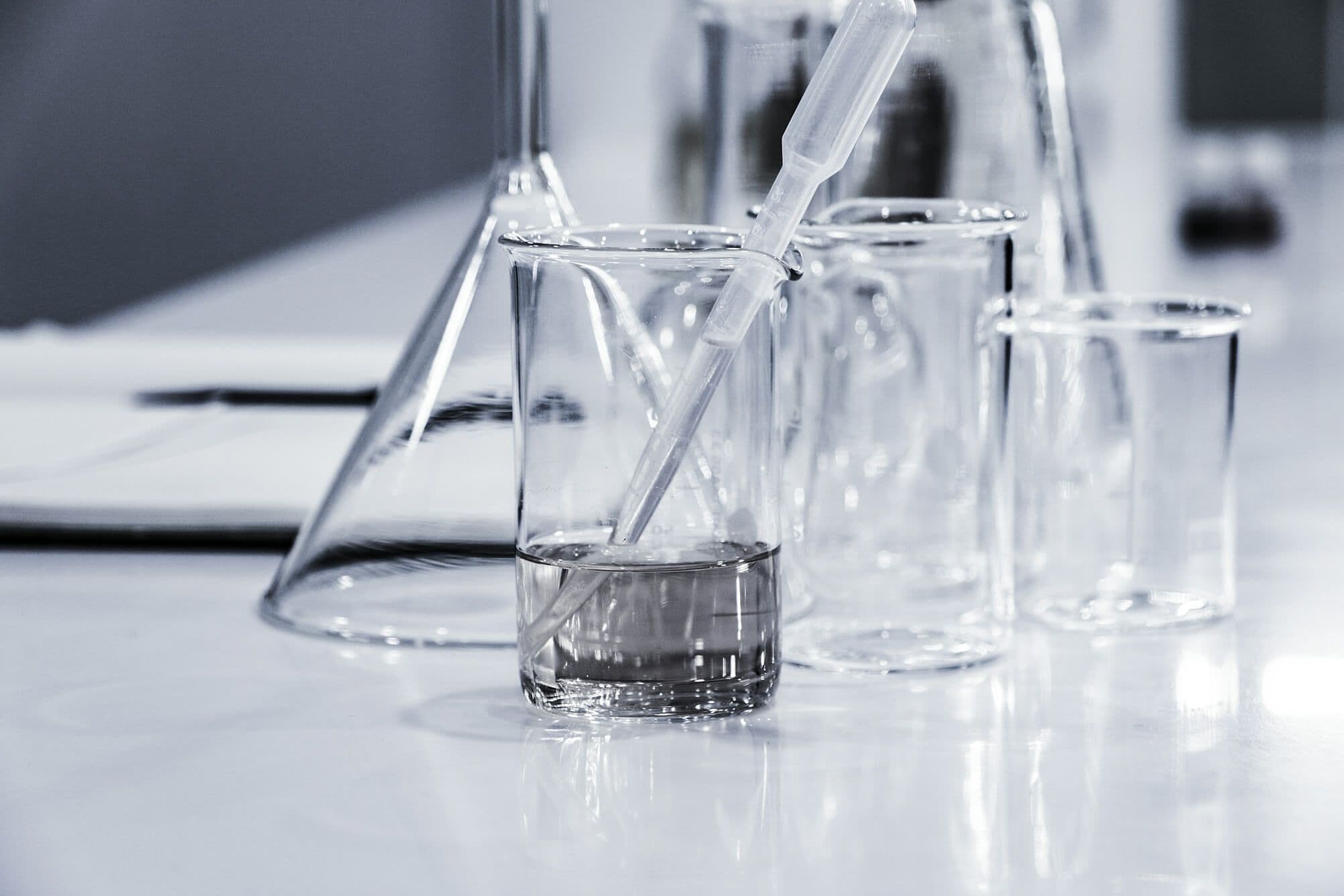 Zlewki, kolba stożkowa i pipeta na białym blacie laboratoryjnym